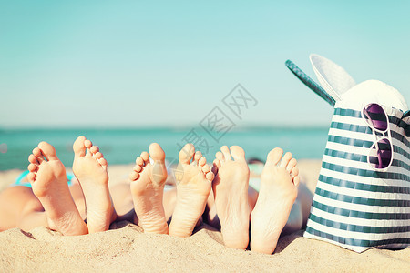 暑假,日光浴修脚的三个女人躺海滩上,戴着草帽,太阳镜袋子图片