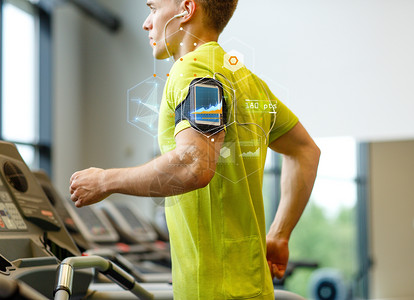 运动,健身,生活方式,技术人的智能手机耳机的人健身房的跑步机上锻炼图片