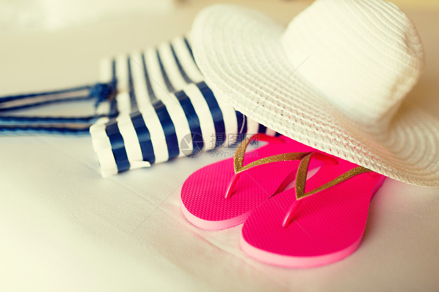 度假度假旅游酒店床上的沙滩袋草帽拖鞋的特写图片