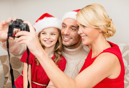 家庭,诞节,幸福人的微笑的家庭诞老人帮助帽子与照片相机拍照图片