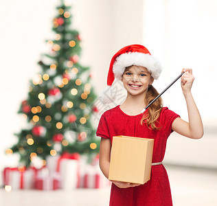诞节,冬天,幸福微笑的女孩戴着诞老人的帽子,带着礼品盒魔杖图片