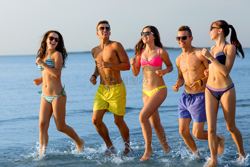 友谊,海洋,暑假,假期人们的群微笑的朋友穿着泳装太阳镜海滩上跑步图片