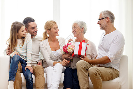 家庭,幸福,世代,假日人们的幸福的家庭,鲜花礼品盒坐家里的沙发上图片
