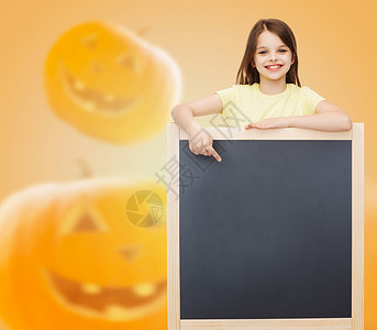 广告,手势,教育,假期人的微笑的小女孩与黑板指向万节南瓜背景图片