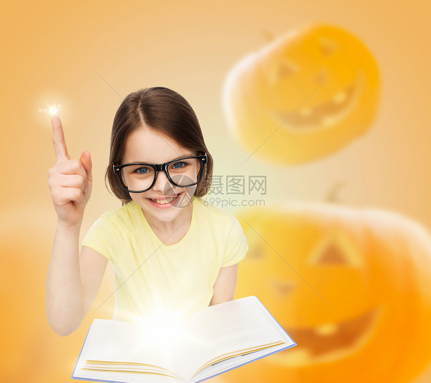 教育,假期,童,视觉人的微笑的小女孩戴着眼镜,带着万节南瓜背景的魔法书图片