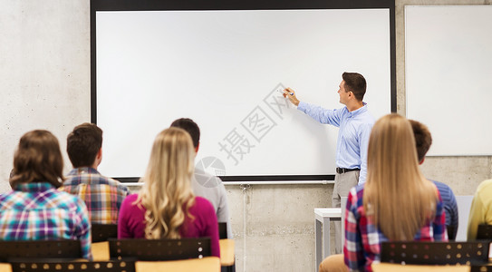 教育,高中,队合作人的微笑的老师站学生前,教室的白板上写些东西背景图片