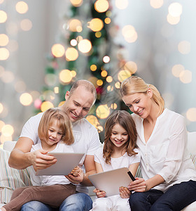 家庭,假期,技术人微笑的母亲,父亲小女孩与平板电脑诞树灯光背景图片