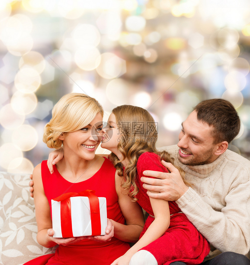 诞节,假期,家庭人的快乐的母亲,父亲小女孩与礼品盒亲吻灯光背景图片