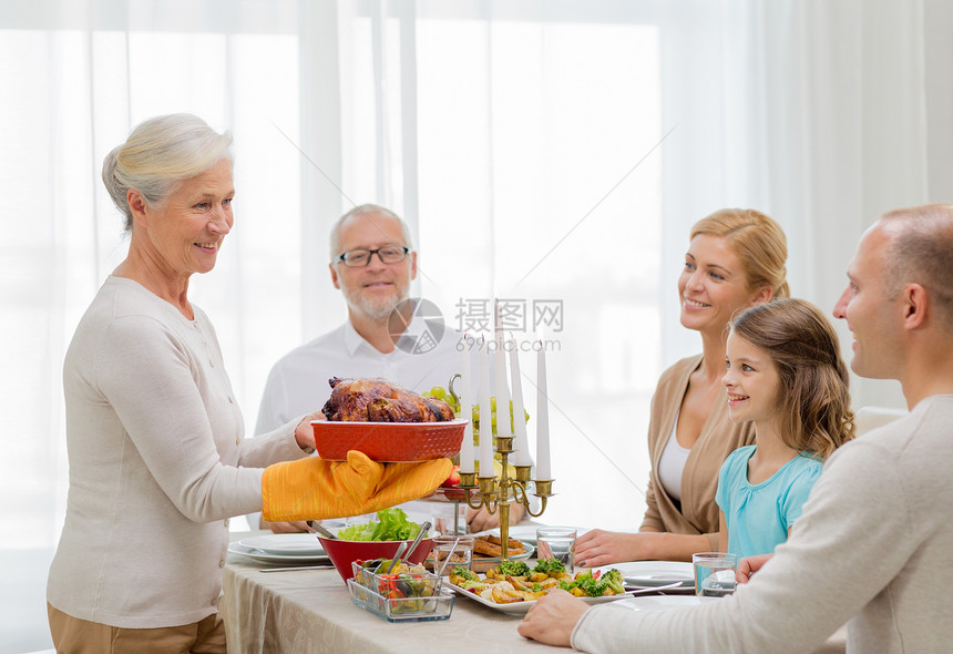 家庭,假期,世代人的微笑的家庭家里吃晚饭图片