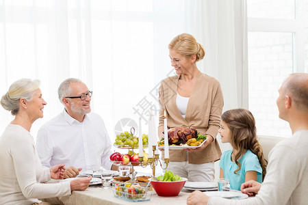 家庭,假期,世代人的微笑的家庭家里吃晚饭图片