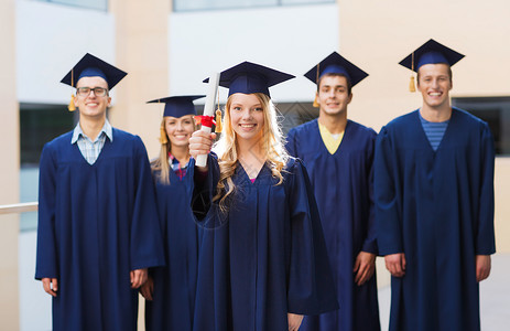 教育,毕业人的群微笑的学生穿着沙黑板长袍与文凭户外图片