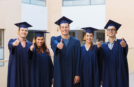 教育,毕业,手势人的群微笑的学生穿着沙黑板长袍,户外竖大拇指图片