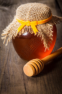 蜂蜜罐子里,桌子上木制滴剂图片