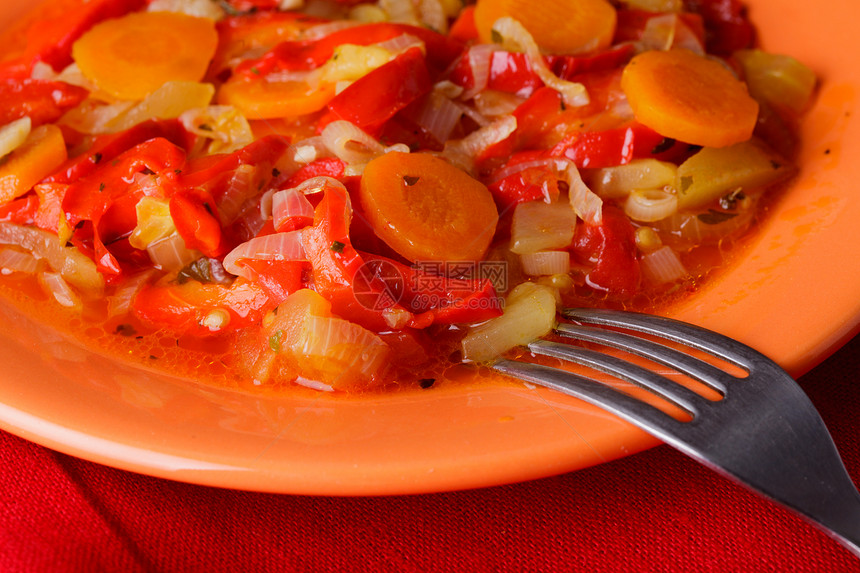 橙色盘子红色餐巾纸上炖蔬菜图片