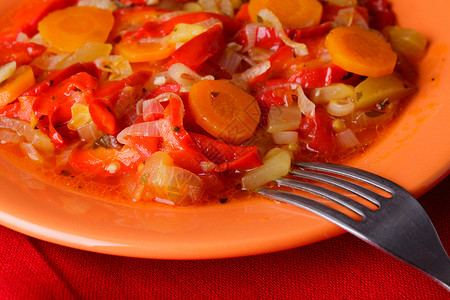 橙色盘子红色餐巾纸上炖蔬菜背景图片