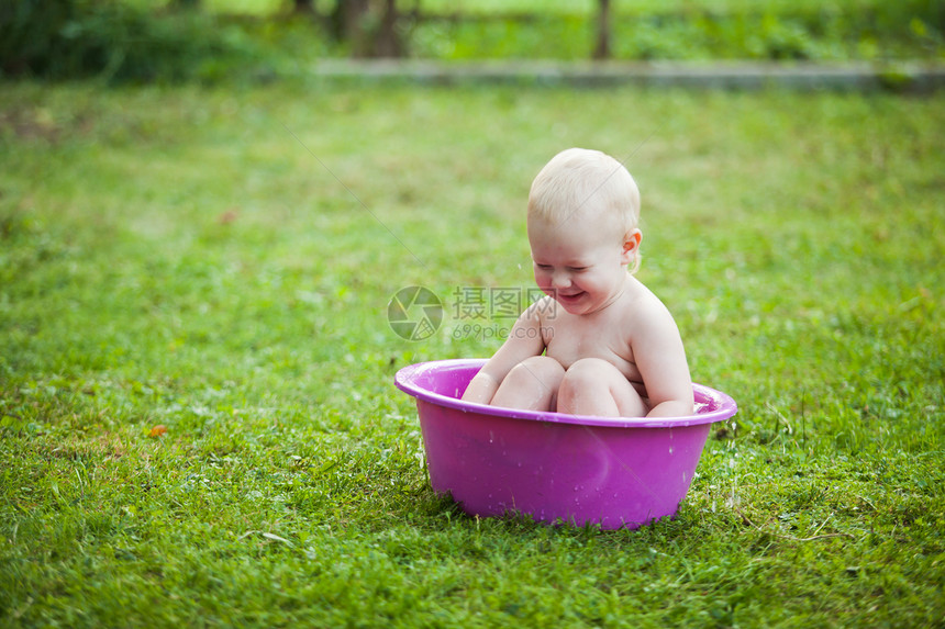 快乐的蹒跚学步的孩子院子里的草地上洗碗图片