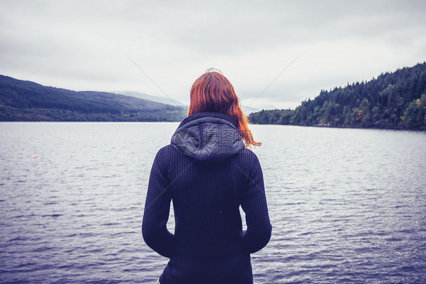 轻的女人欣赏湖的宁静图片