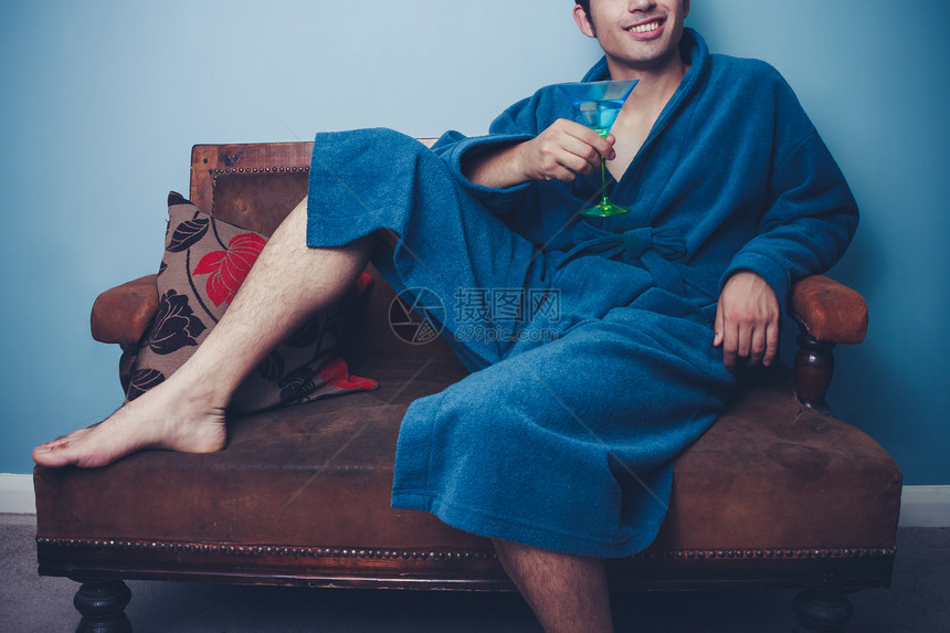穿着浴袍的轻人沙发上喝鸡尾酒图片
