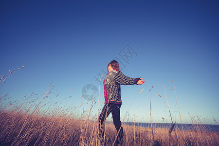 日落时,女人海边的田野里奔跑图片