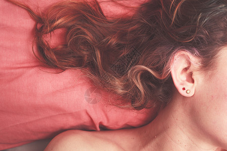 轻的女人躺床上,头发散落枕头上背景图片