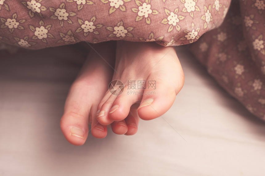 轻女人的脚床底下的被子里图片