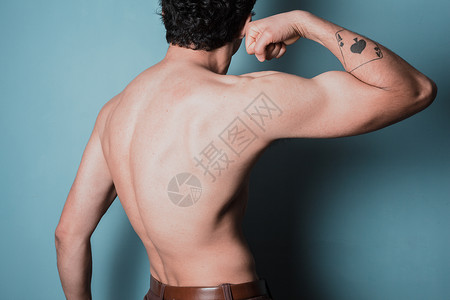 纹身男个肌肉发达的轻人弯曲手臂的后视镜背景