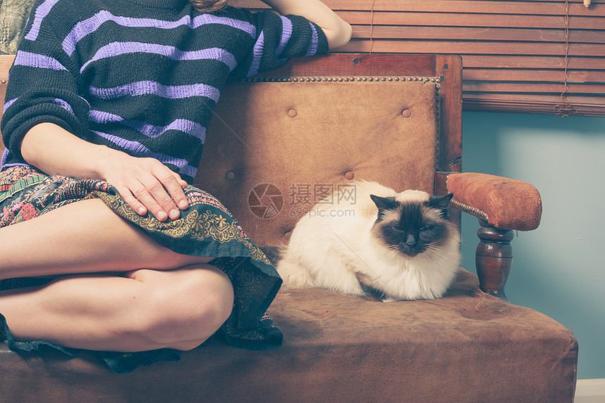 个轻的女人她的猫坐沙发上图片