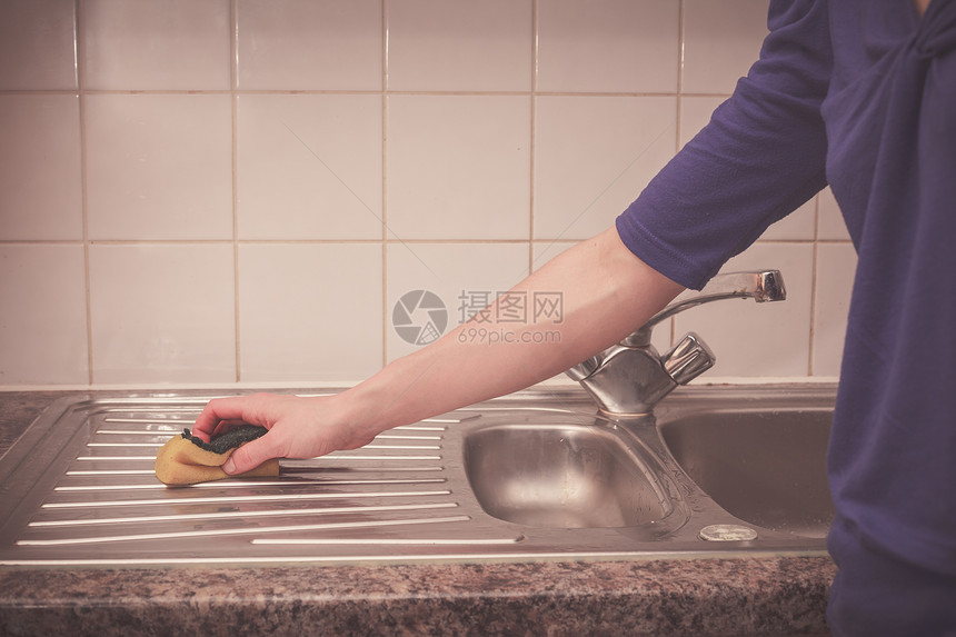 个轻的女人正厨房水槽周围打扫卫生图片