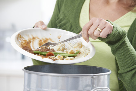 50代女人把食物剩菜刮进垃圾桶背景