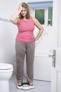 超重的女人浴室里用秤称重图片