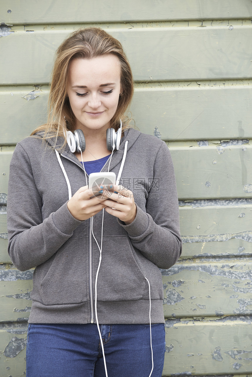 十几岁的女孩戴着耳机,城市环境中听音乐图片