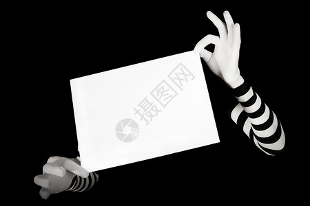 戴条纹手套的手着个白色的空白页,孤立黑色背景上图片