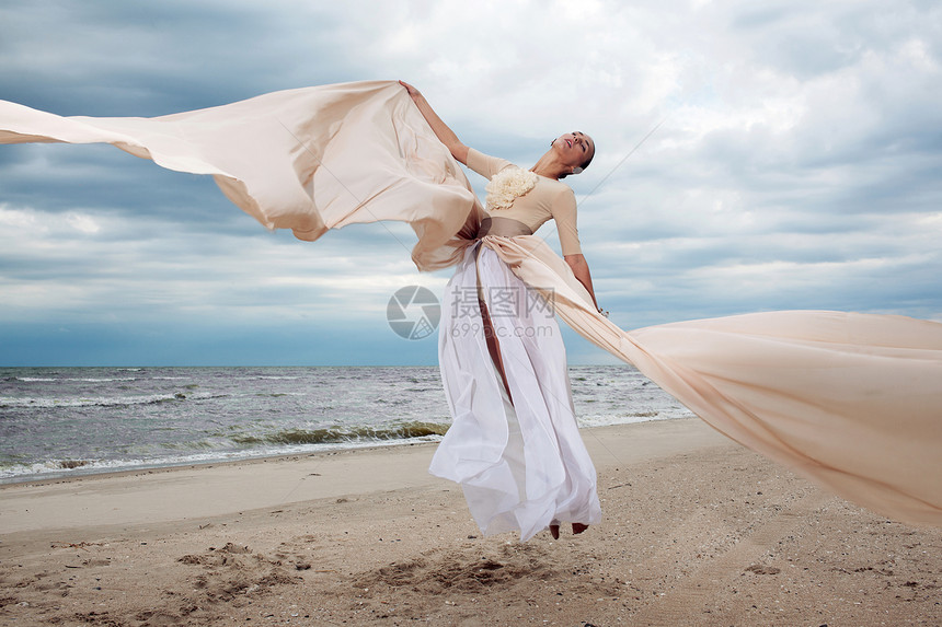 模特穿着长裙跳来,就像海滩上的翅膀图片