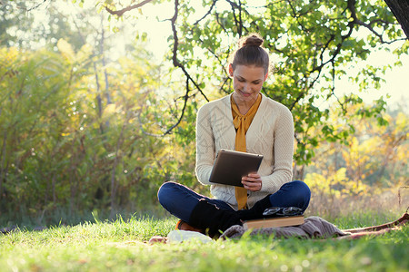远程教育坐着的女人秋天的户外玩iPad图片