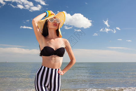 时尚的女人穿着时尚的泳衣海滩上图片