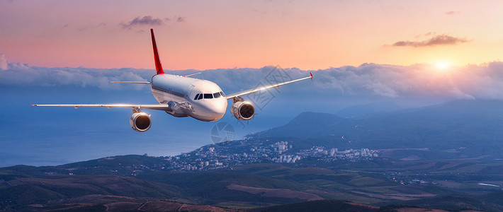 正山小种乘客飞机白色飞机的景观橙色的天空中飞行,云层覆盖着群山,大海五颜六色的日落客机正降落商业飞机私人飞机旅背景
