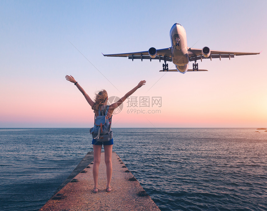 日落时的飞机女人夏天的风景,女孩站海上码头,举手臂飞行的客机女人降落商业飞机黄昏生活方式旅行图片