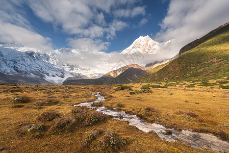 美丽的风景高山,积雪覆盖的山峰,小河,黄草多云的天空五颜六色的日出山谷尼泊尔喜马拉雅山脉的惊人景象自然背景图片