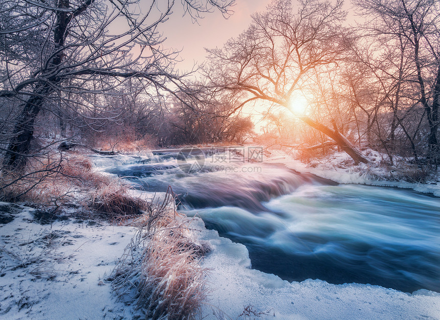 日落时令人惊叹的河流的冬季森林冬天的风景雪树,冰,美丽的冰冻河流,雪丛,黄昏中五颜六色的天空模糊的水小瀑布水图片