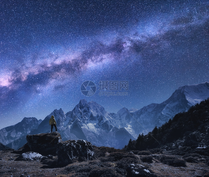 银河山脉的尼泊尔的夜晚,站石头上的人,山脉星空岩石上雪峰,天空上星星徒步旅行夜风景与明亮的银图片
