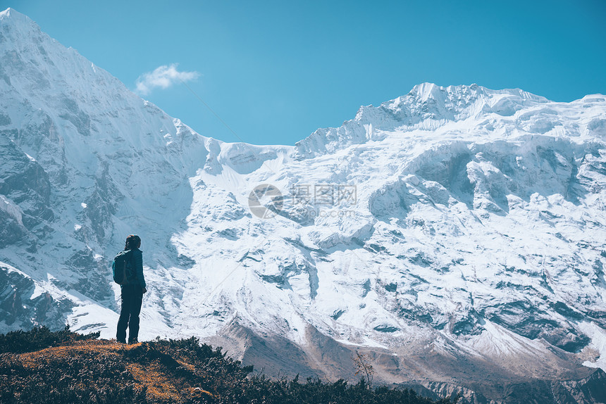 站山上的轻女人,日落时看着白雪覆盖的岩石风景与女孩,高山与雪山,小径,蓝天尼泊尔旅行复古风格自然图片