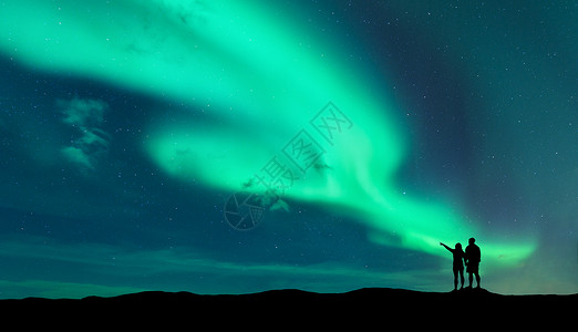 谁与争锋金属字北极光站立的男人女人谁指着北极光的轮廓挪威洛福腾群岛极光天空星星北极光夜间景观与极光夫妇背景
