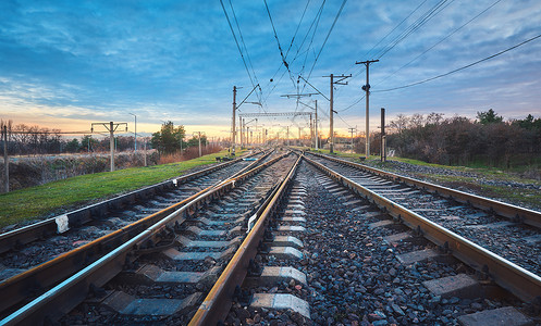 日落时的铁路火车站抗蓝天工业景观与铁路,多云的天空,绿草,树木铁路枢纽重工业货物运输货运运铁路背景图片