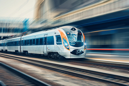 欧洲日落时火车站上运行的高速客运列车运动模糊效应的铁路站台现代城际列车铁路的城市场景铁路运输高速客运列车背景图片