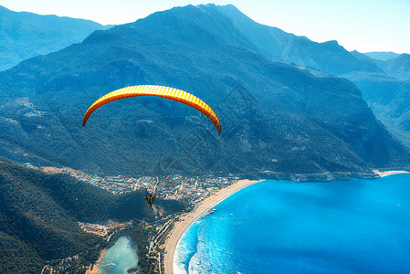 滑翔天空中滑翔伞阳光明媚的日子里,与蓝色的水山脉飞越大海鸟瞰滑翔伞蓝色泻湖奥卢德尼兹,土耳其极限运动背景图片