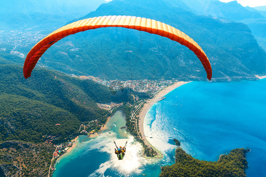 滑翔天空中滑翔伞阳光明媚的日子里,与蓝色的水山脉飞越大海鸟瞰滑翔伞蓝色泻湖奥卢德尼兹,土耳其极限运动图片