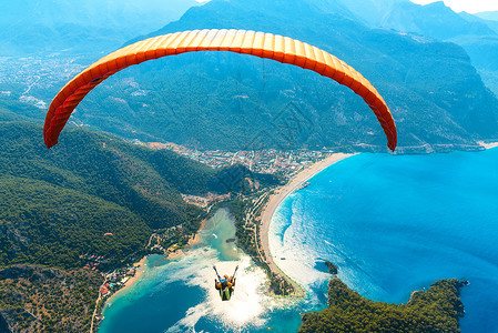 蒙塞尼滑翔天空中滑翔伞阳光明媚的日子里,与蓝色的水山脉飞越大海鸟瞰滑翔伞蓝色泻湖奥卢德尼兹,土耳其极限运动背景