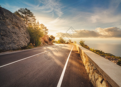欧洲日落时的山路风景与岩石,晴朗的天空与云美丽的沥青路晚上的夏天丰富多彩的旅行背景山区的高速公路运输欧洲背景图片