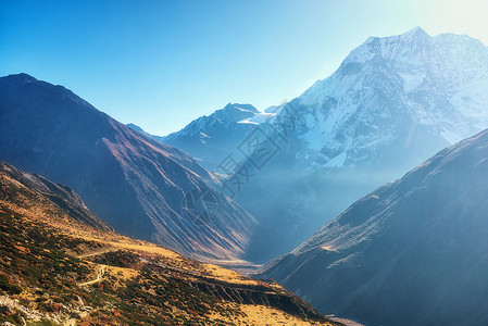 比利茨基高峰美丽的山谷景色尼泊尔日出时,风景与山丘小径白雪覆盖的山着蓝天早上喜马拉雅山的雪峰神奇的喜马拉雅山自然美背景