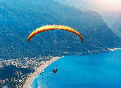 滑翔天空中滑翔伞串联飞行海上与蓝色的水,海滩山脉日出鸟瞰滑翔伞蓝色泻湖奥卢德尼兹,土耳其极限运动景观背景图片